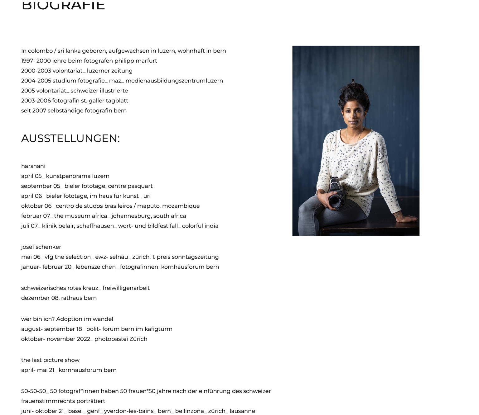 carmela harshani odoni sitzt mit ihrer Kamera vor einem blauen Hintergrund